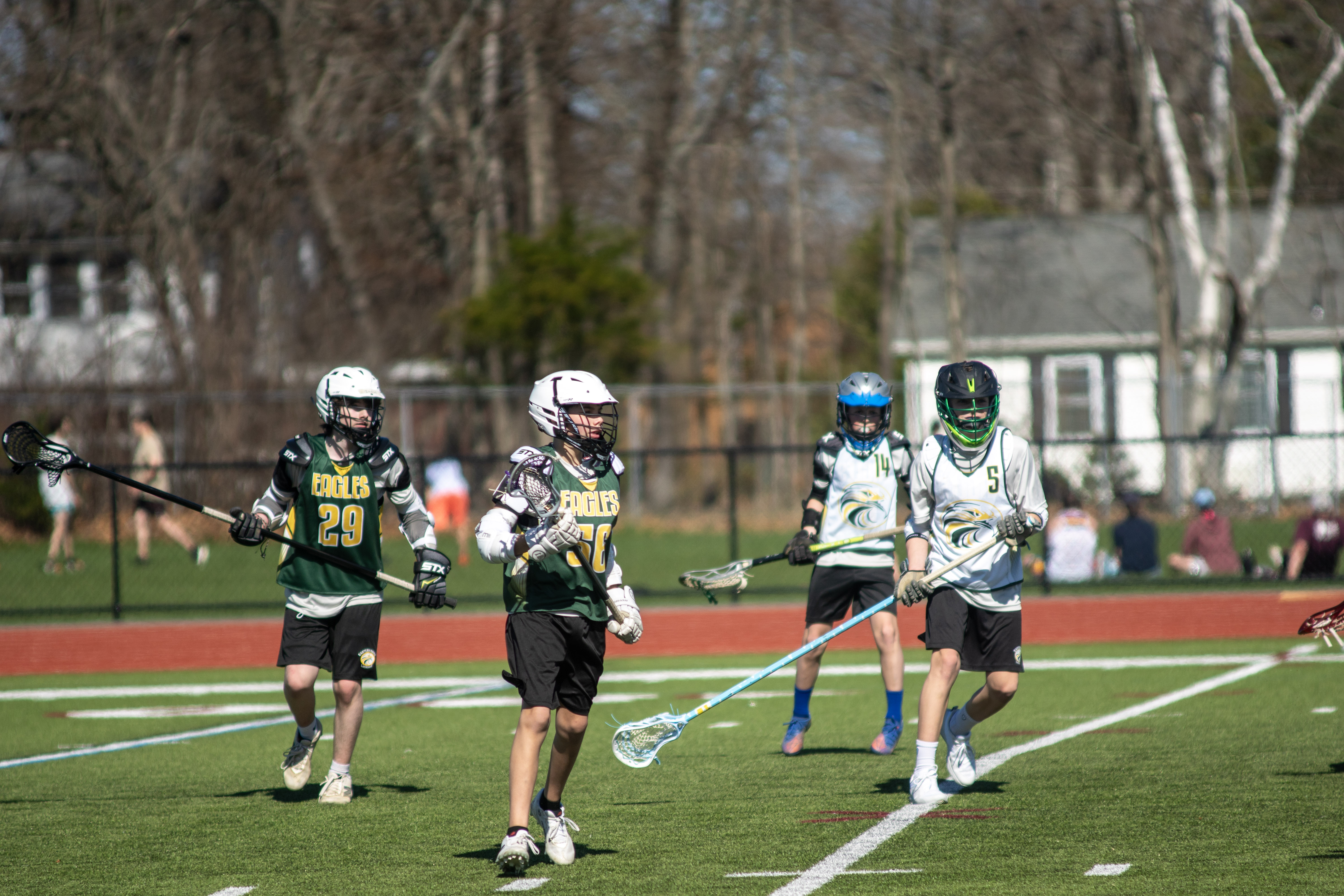 Youth lacrosse players in action on a sunny Maine field.